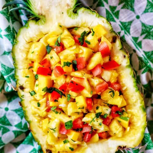 chopped pineapple, mango, tomatoes, and onions in a hollowed out pineapple.