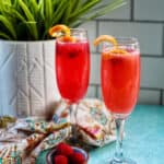 two raspberry mimosas in champagne flutes.
