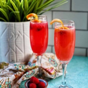 two raspberry mimosas in champagne flutes.