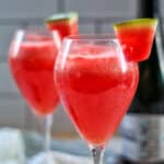 two glasses of watermelon mimosas with slice of watermelon garnish.