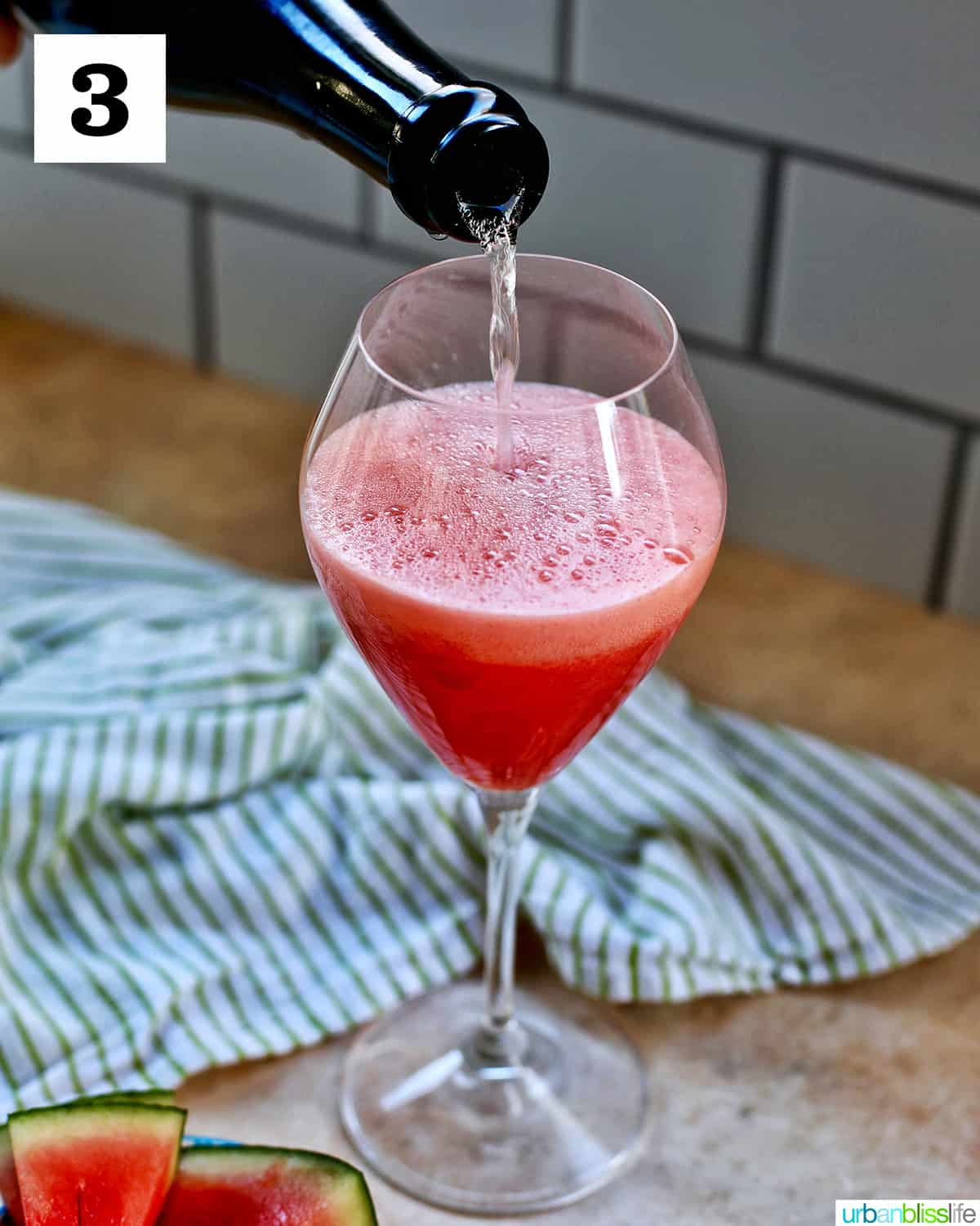 pouring champagne into a glass of watermelon mimosa.