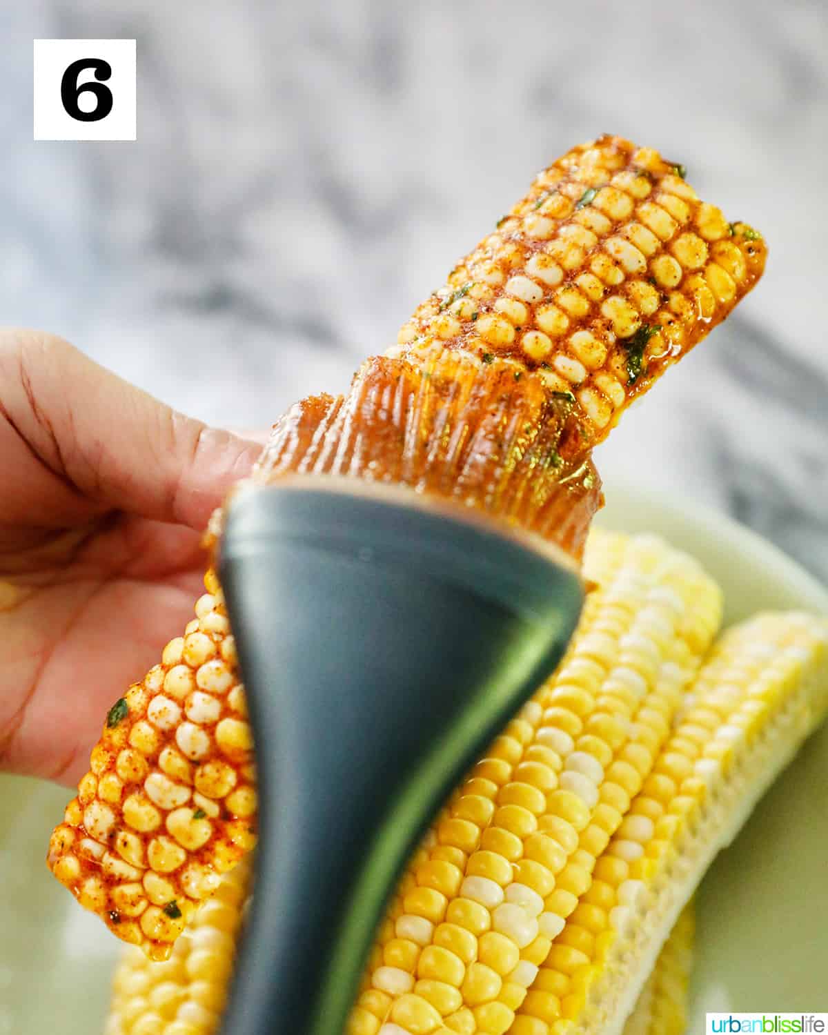 basting a corn rib with seasoned sauce.