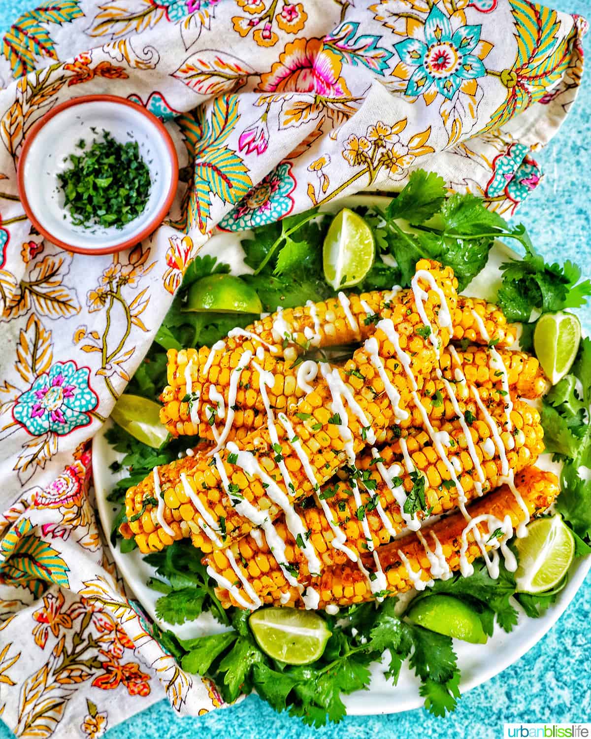 several air fryer corn ribs stacked on top of a bed of greens with drizzled mayo and chopped cilantro.