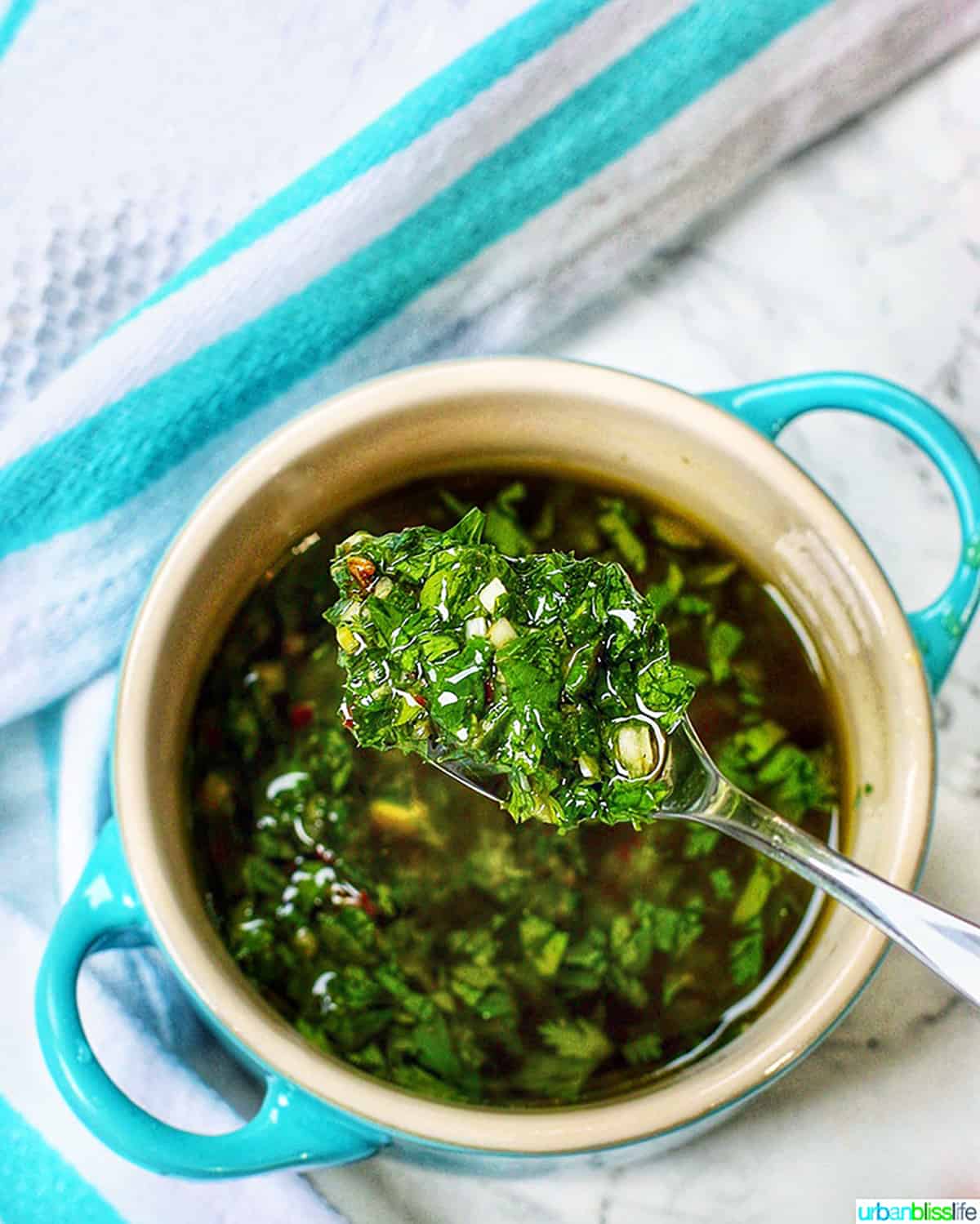 easy chimichurri sauce in spoon over blue dish.