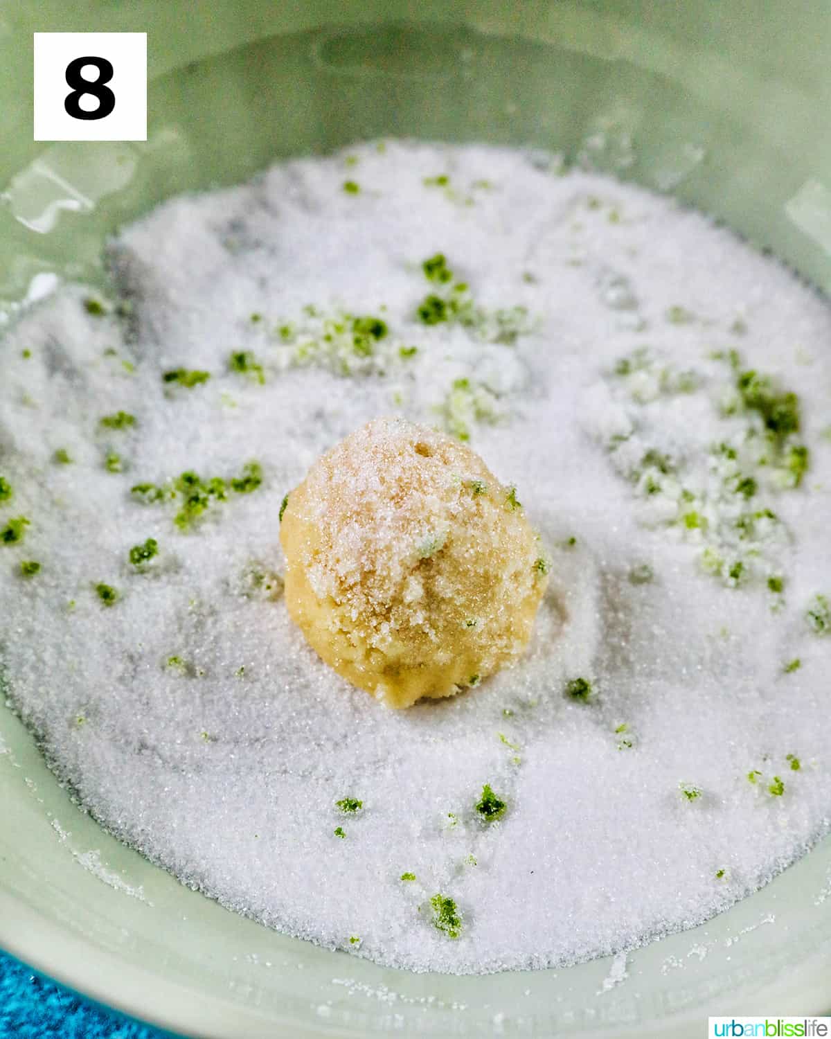 rolling a key lime cookie dough ball into granulated sugar with key lime zest.