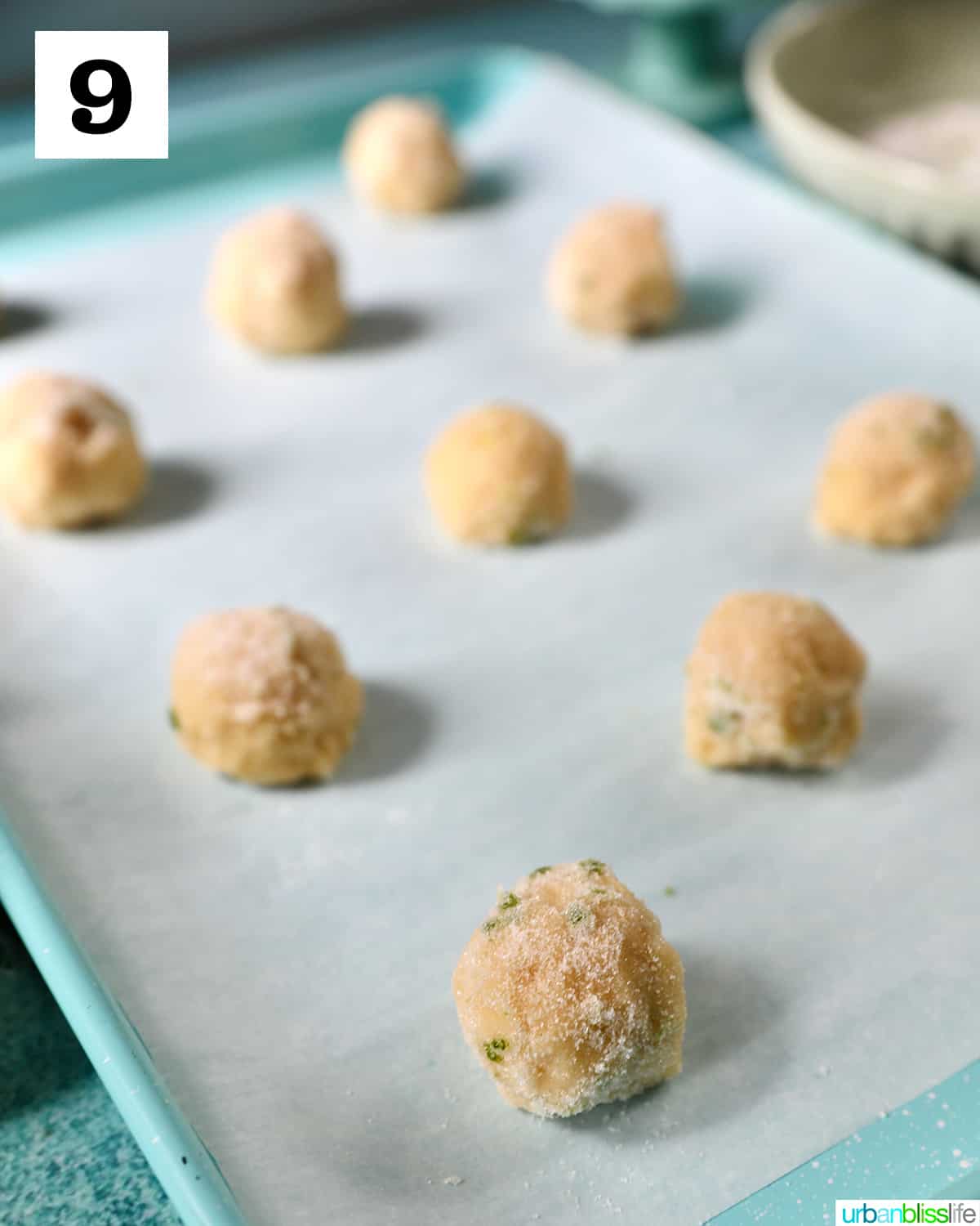 key lime cookie dough balls rolled in granulated sugar placed on a parchment paper-lined baking sheet.