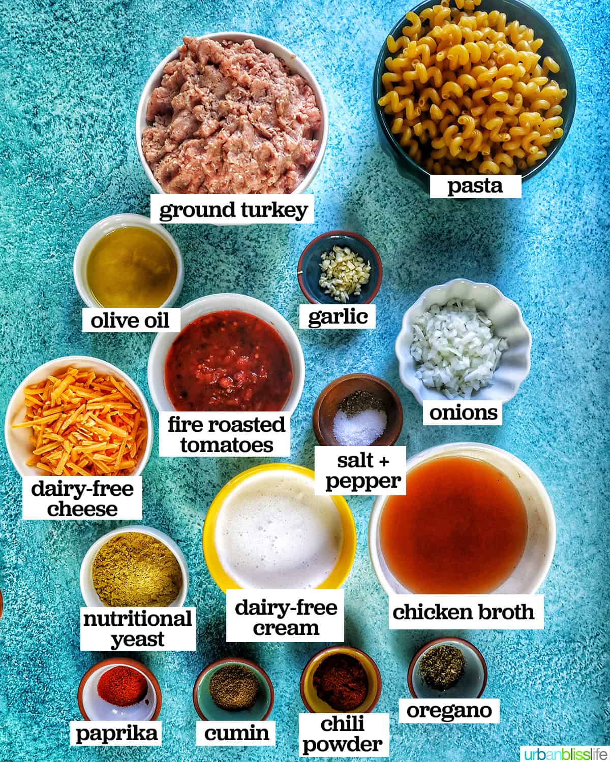 ingredients in bowls to make one pot cheeseburger pasta dairy free on a bright blue background.
