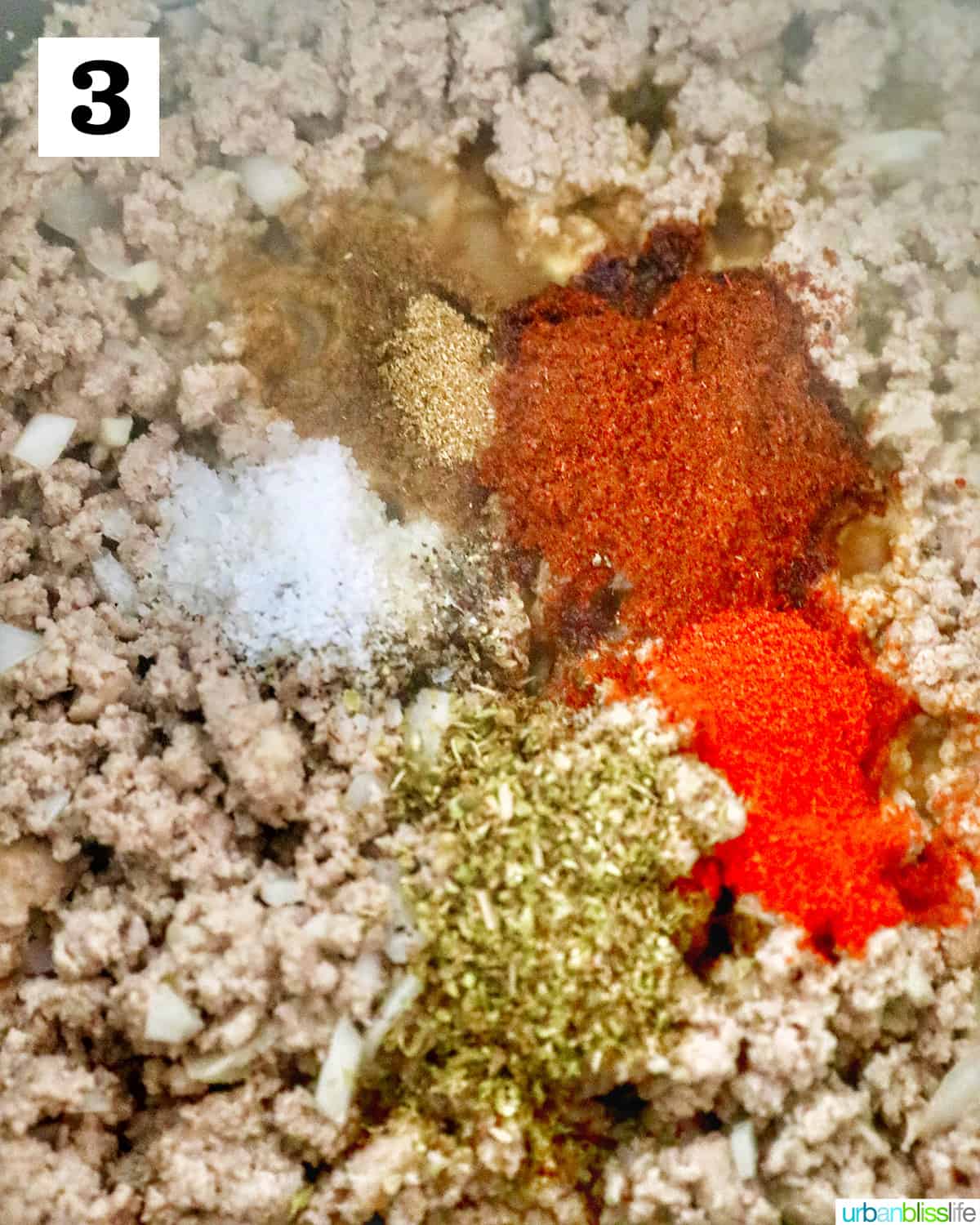 spices sprinkled over ground meat cooking in a dutch oven.