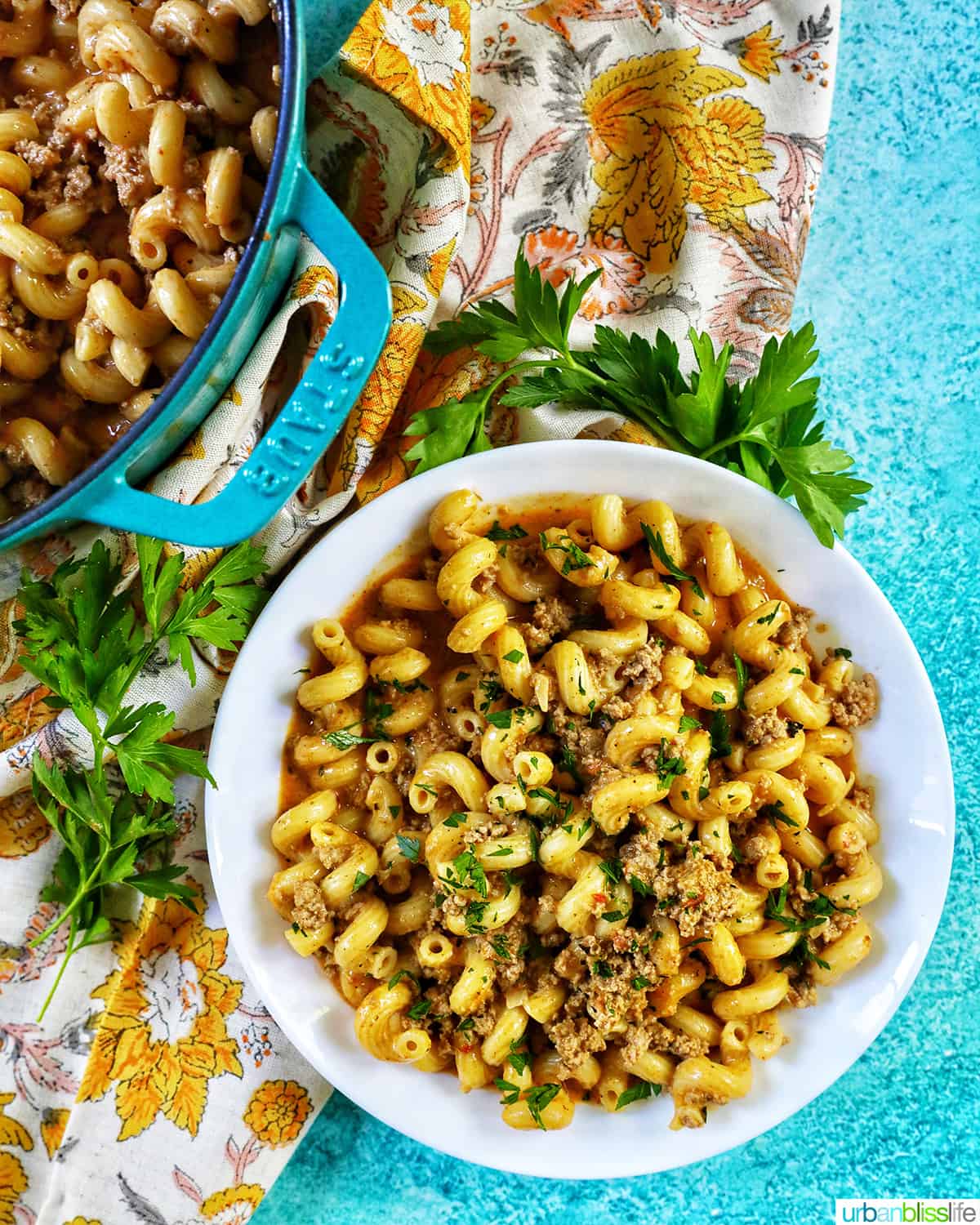 white bowl with forkful of dairy free cheeseburger pasta on a blue background