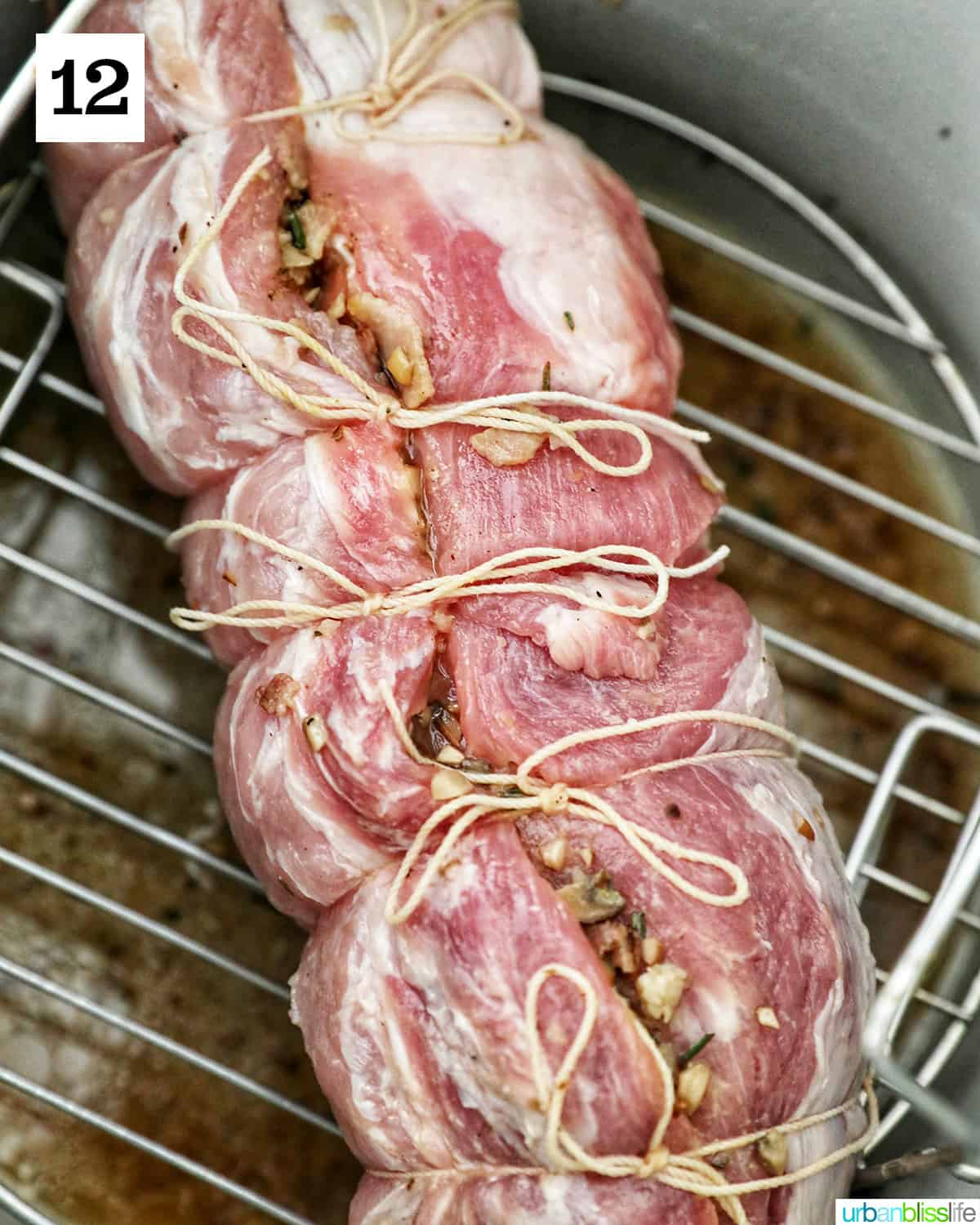 raw stuffed and rolled pork loin wrapped in kitchen twine on a rack in the instant pot.