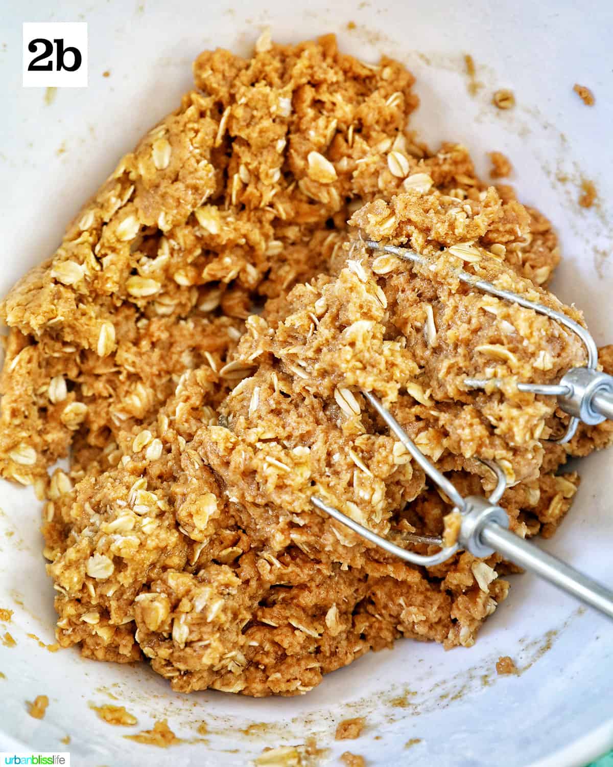 oats, peanut butter, flour, and other ingredients mixed together to make dog donuts with mixing whisks in the bowl.