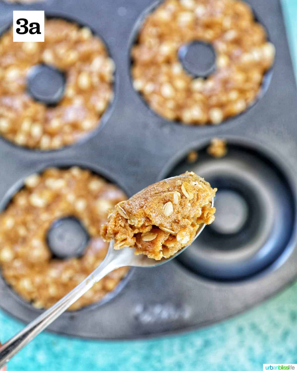 spoonful of dog donut batter over a donut pan with most filled with dog treat batter.