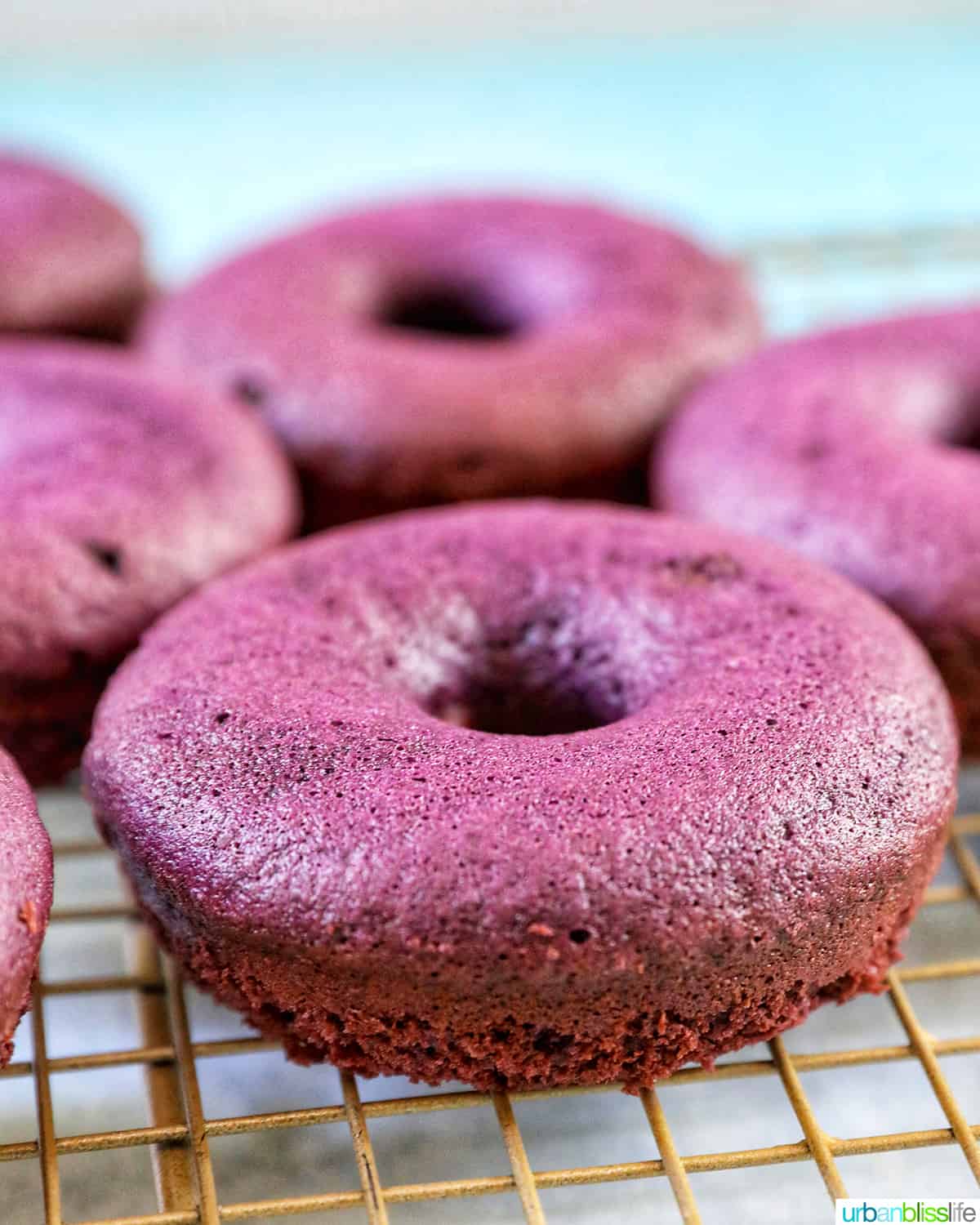 purple ube donuts baked and on a baking rack.