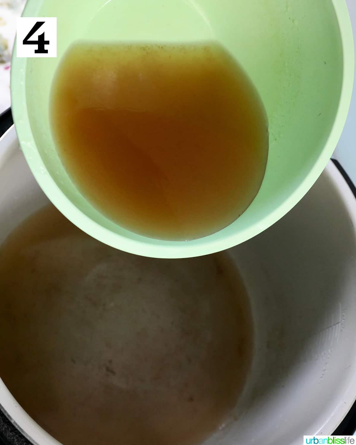 hand adding broth to the inside pot of a ninja foodi or instant pot.