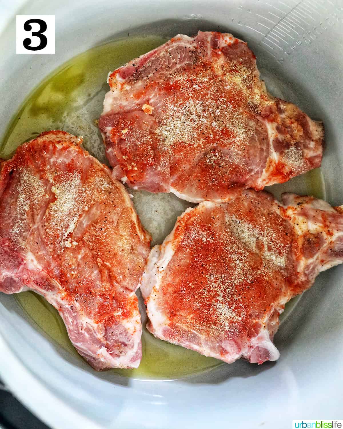three seasoned pork chops sauteing in the inside pot of a ninja foodi or instant pot.
