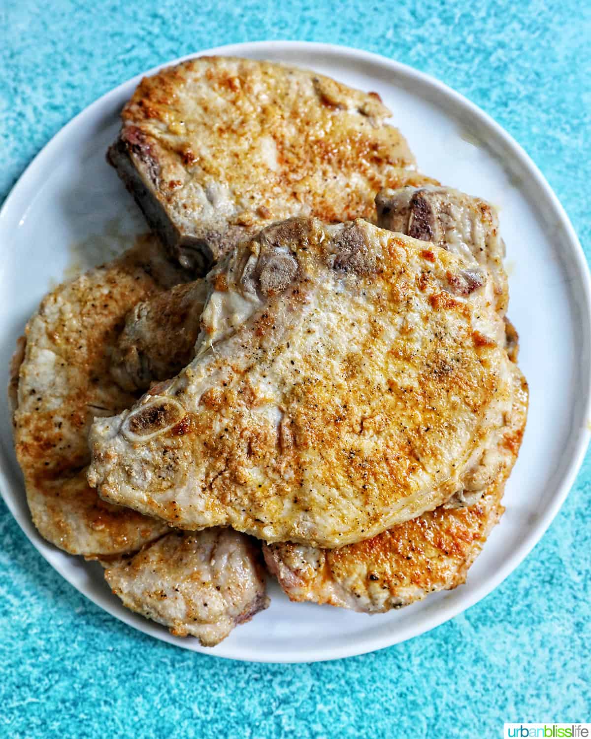 pork chops on a plate on a bright blue background.