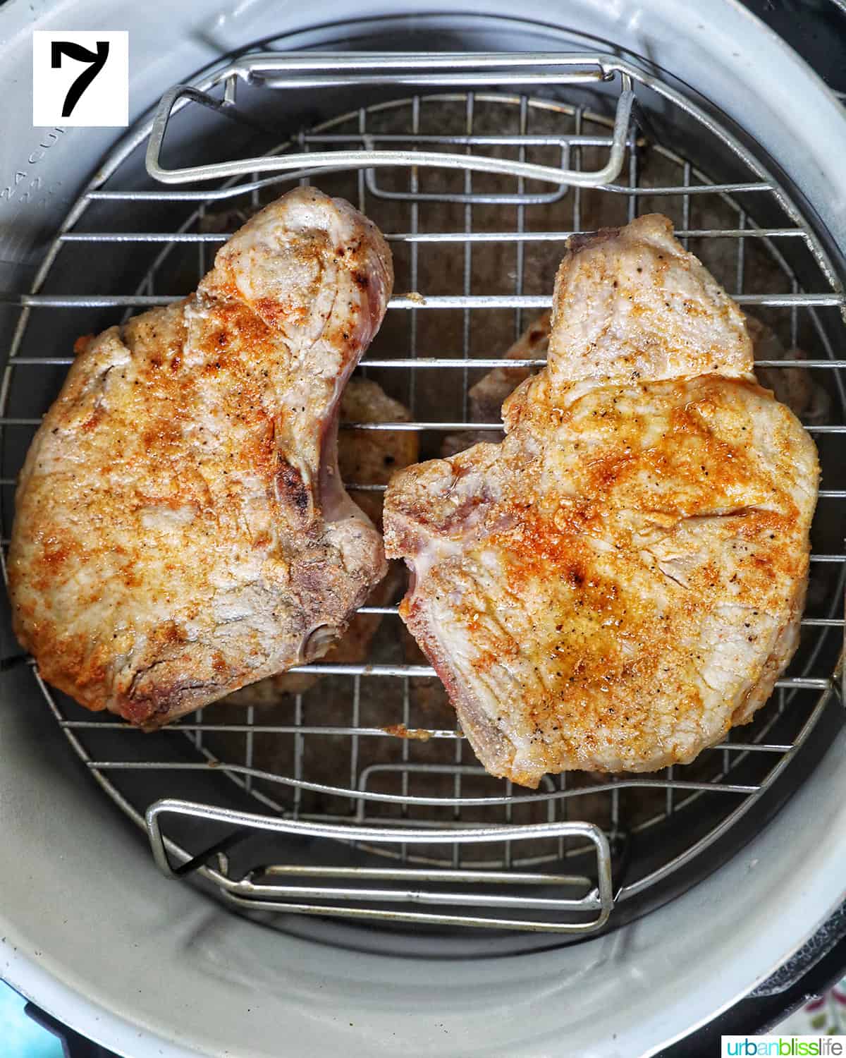 two seasoned pork chops on top of a rack inside a ninja foodi pressure cooker.