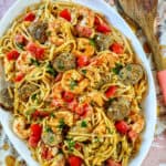 large serving platter of shrimp and sausage pasta with wooden spoon.