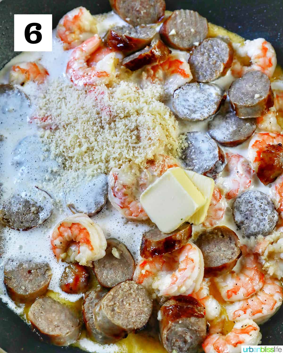 butter and cheese added to shrimp and sausage in a skillet.
