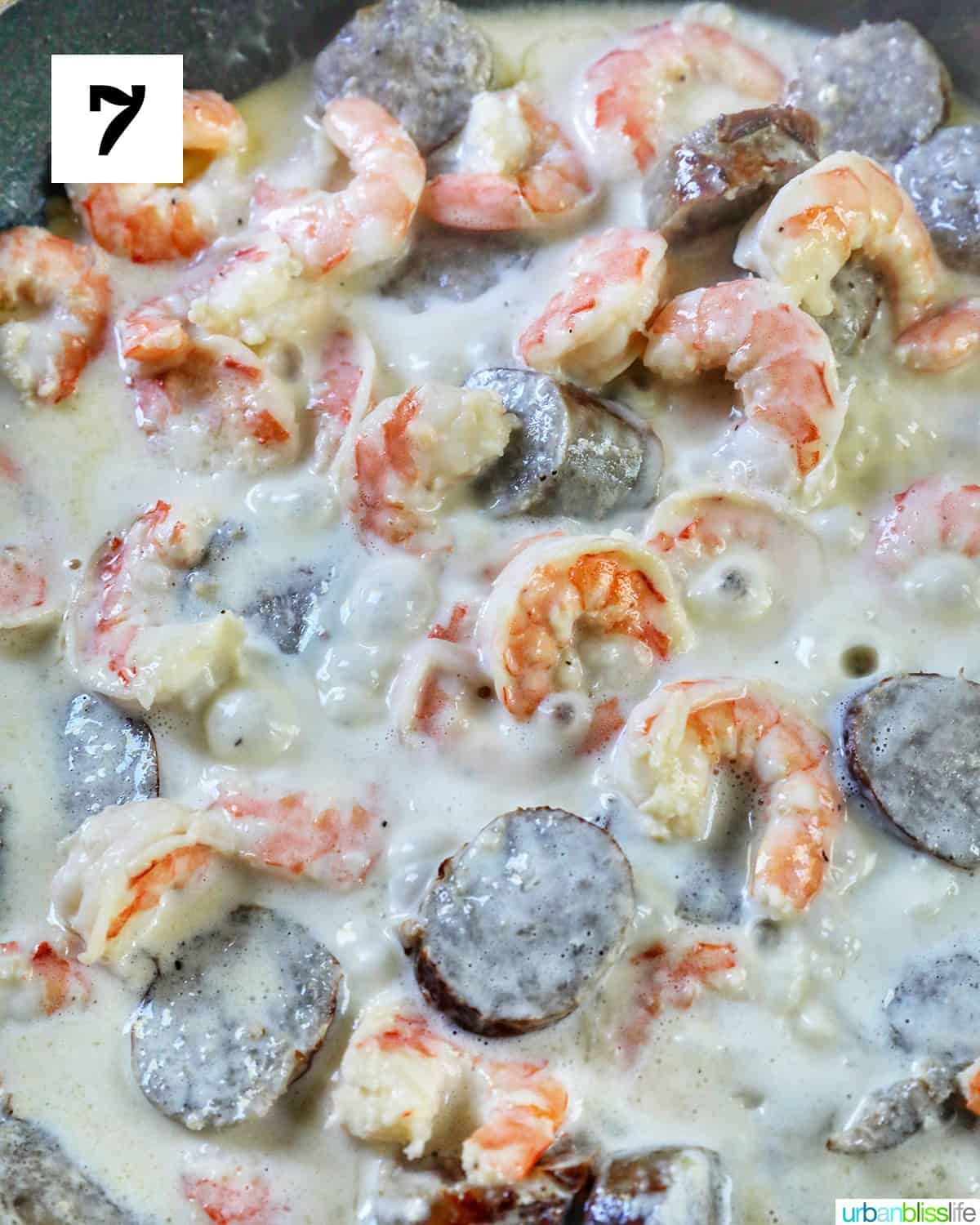 cream added to shrimp and sausage in a skillet.