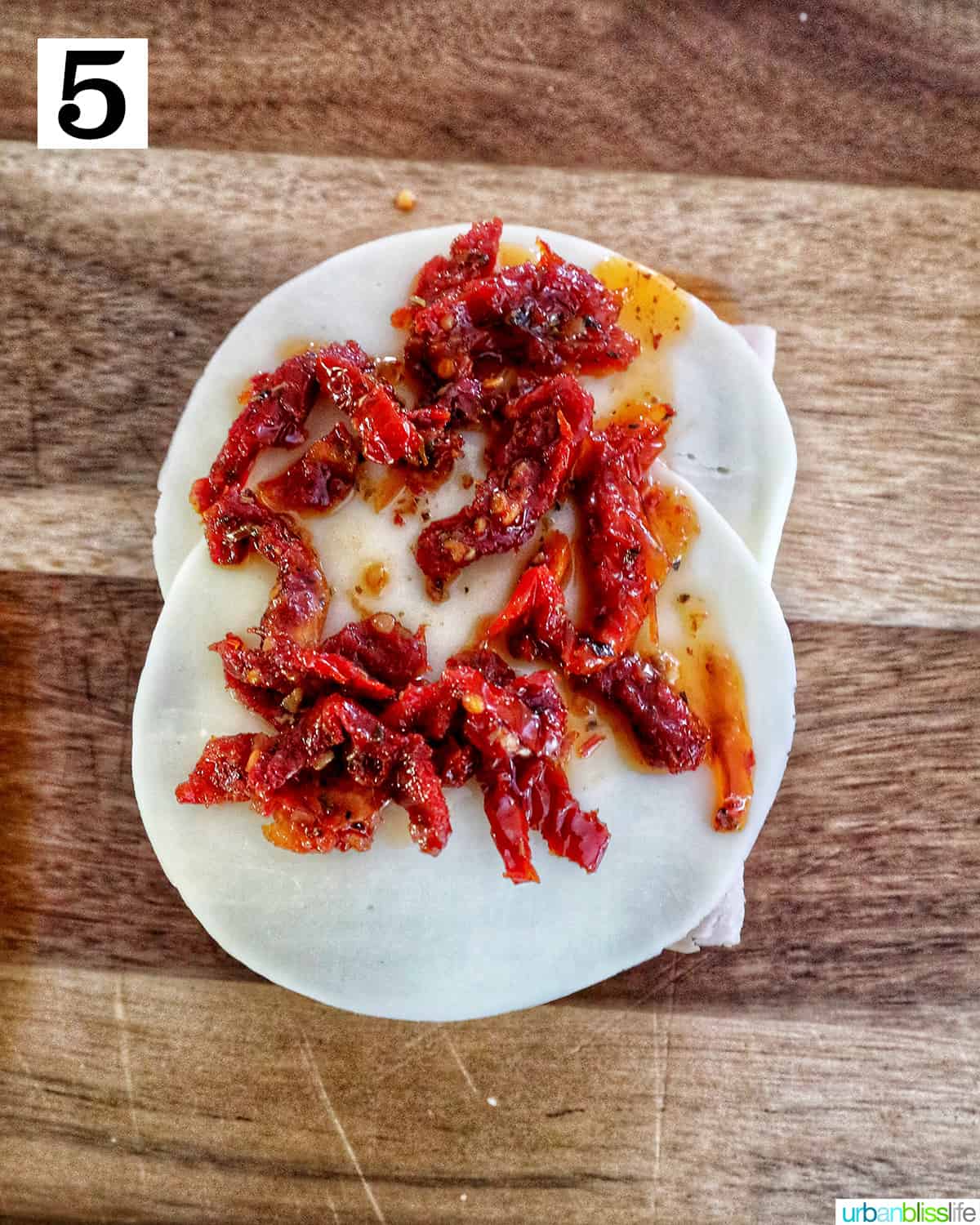 sundried tomatoes on top of provolone cheese to make a turkey pesto sandwich.