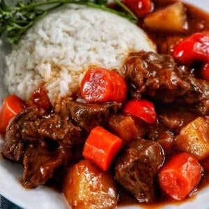 bowl of Filipino beef mechado with white rice and parsley.