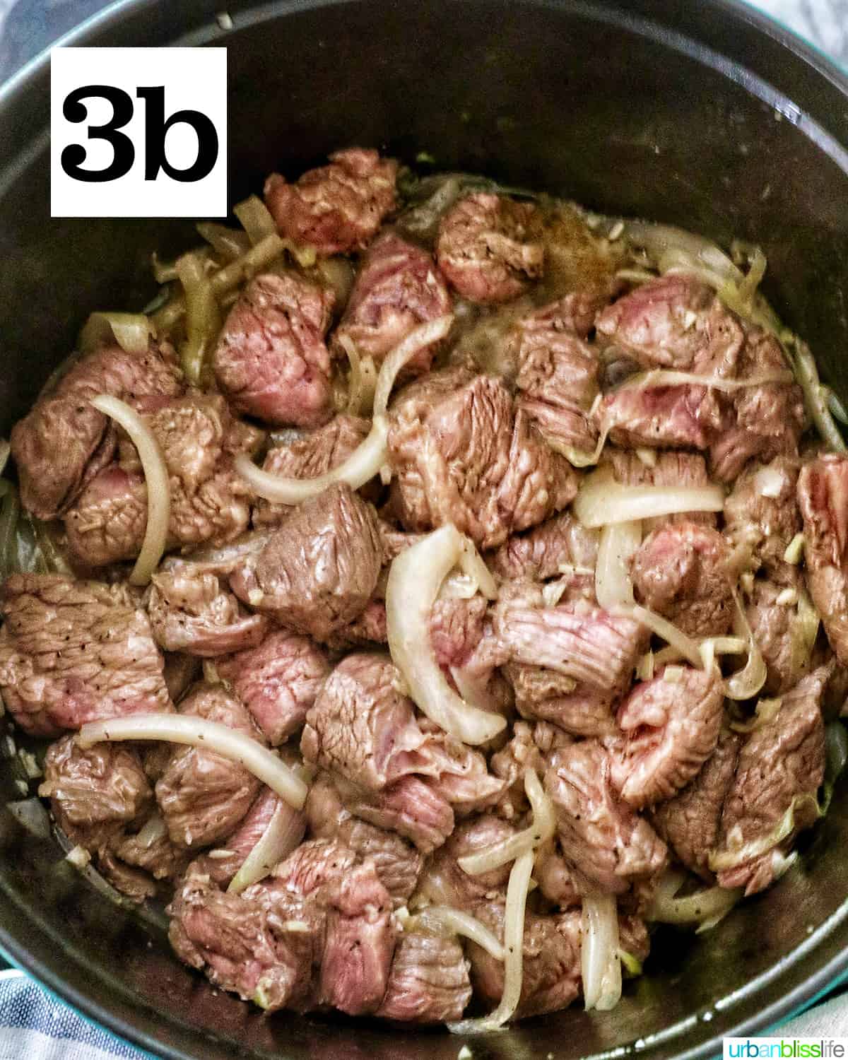 beef browned on all sides with potatoes and garlic in a dutch oven.