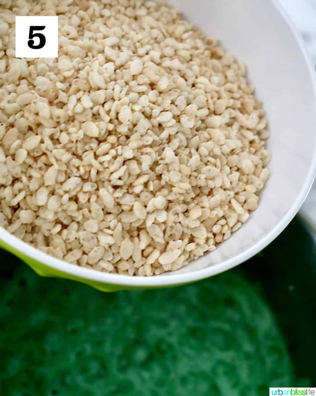 adding rice krispies to green marshmallow mix