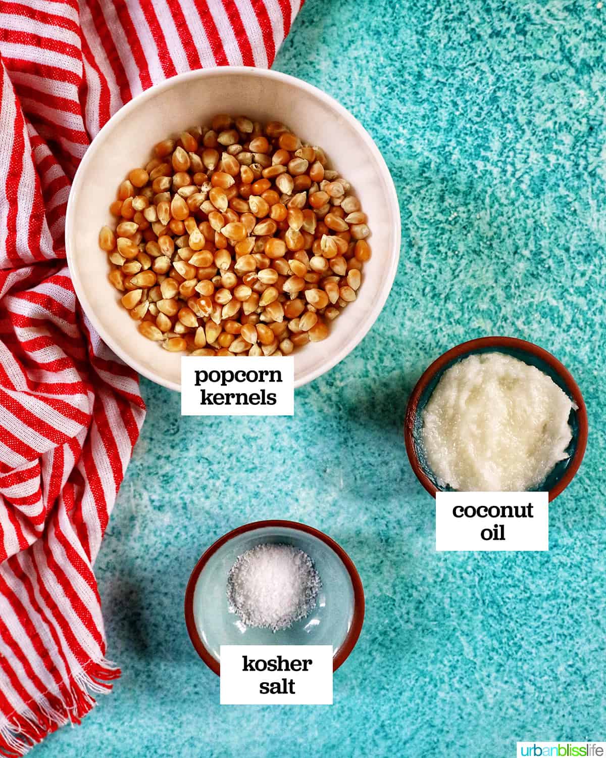 three bowls of ingredients to make Instant Pot Popcorn on a blue table with red and white napkin.