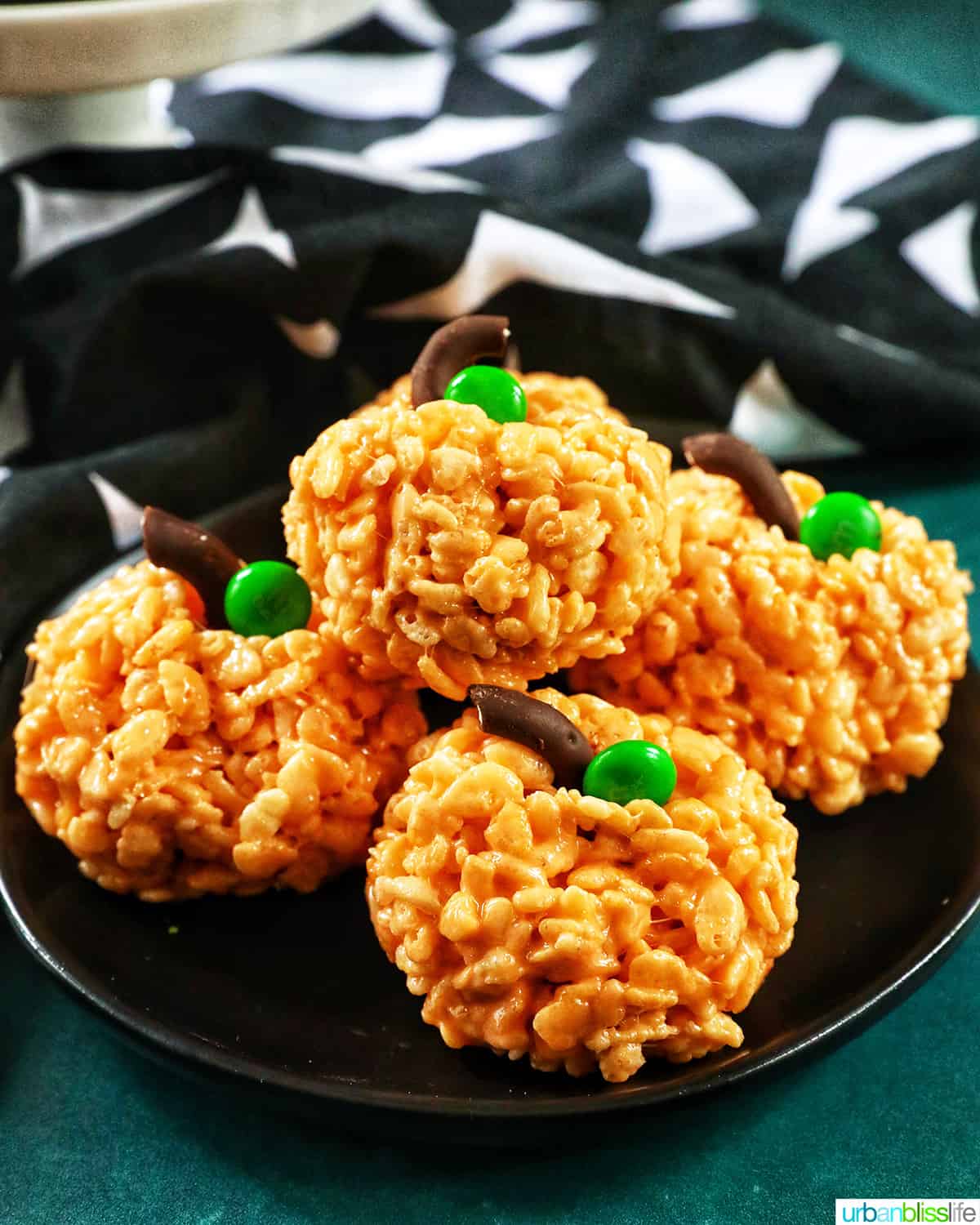 orange pumpkin rice krispie treats on a black plate.