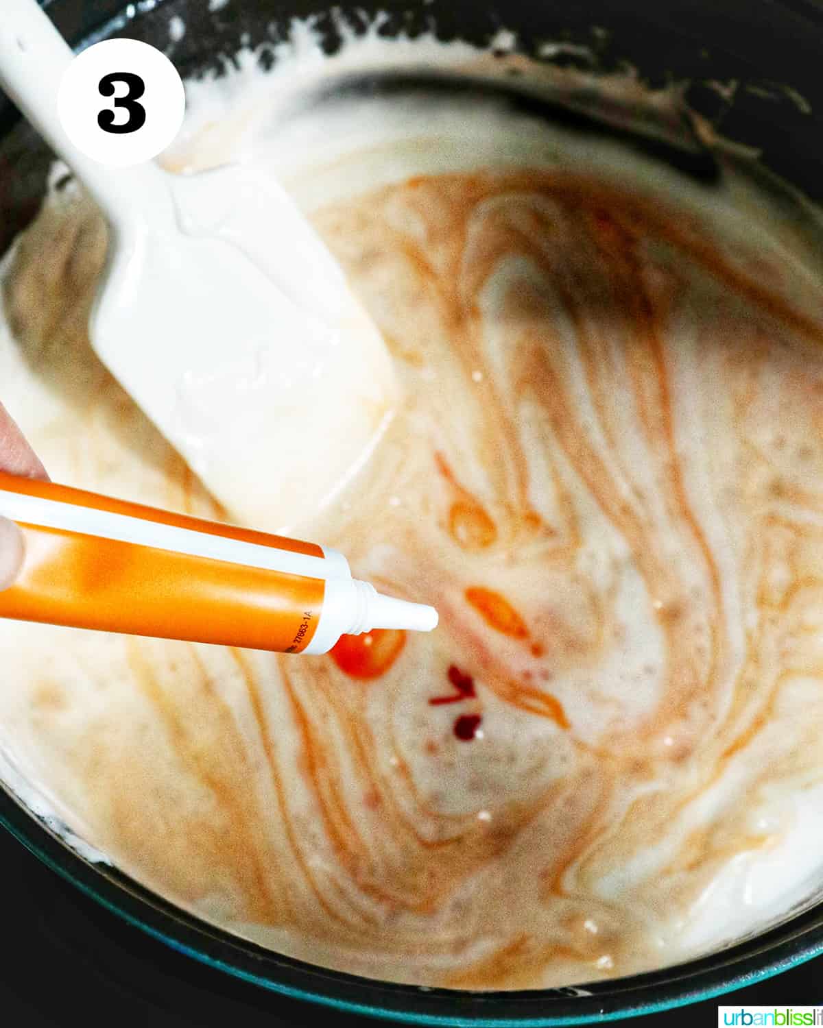 adding orange food color to melted marshmallows in a dutch oven.