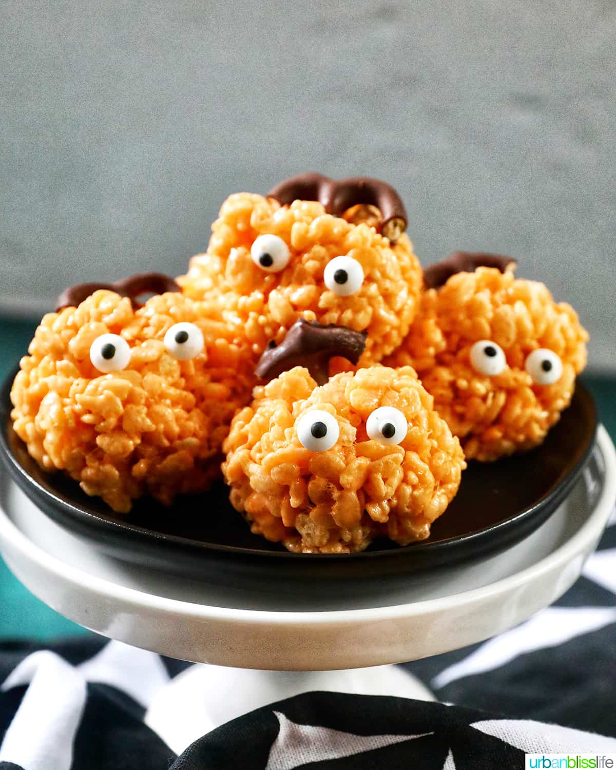 orange pumpkin rice krispie treats on a black plate.