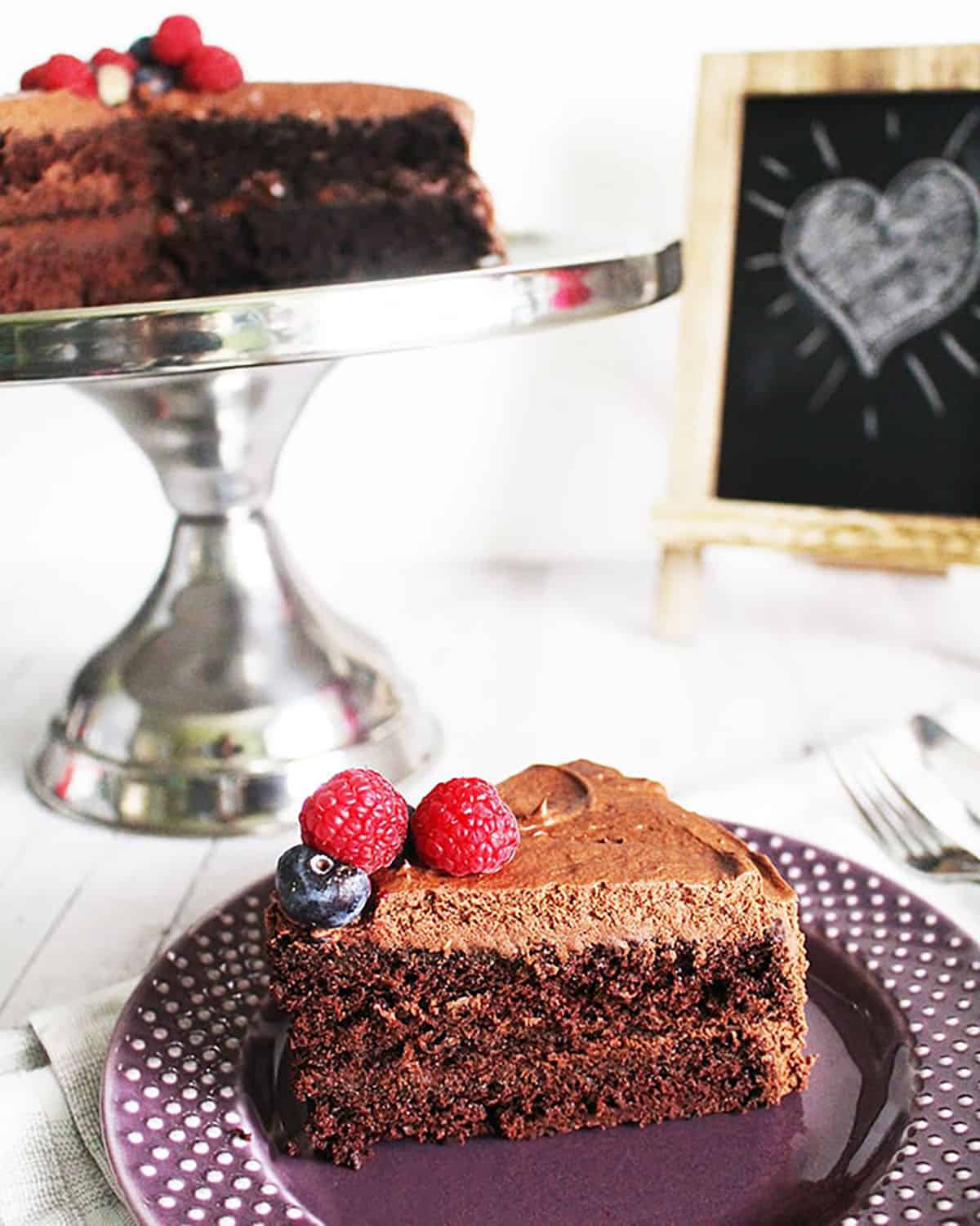 vegan chocolate cake slices on a purple plate and a cake pedestal