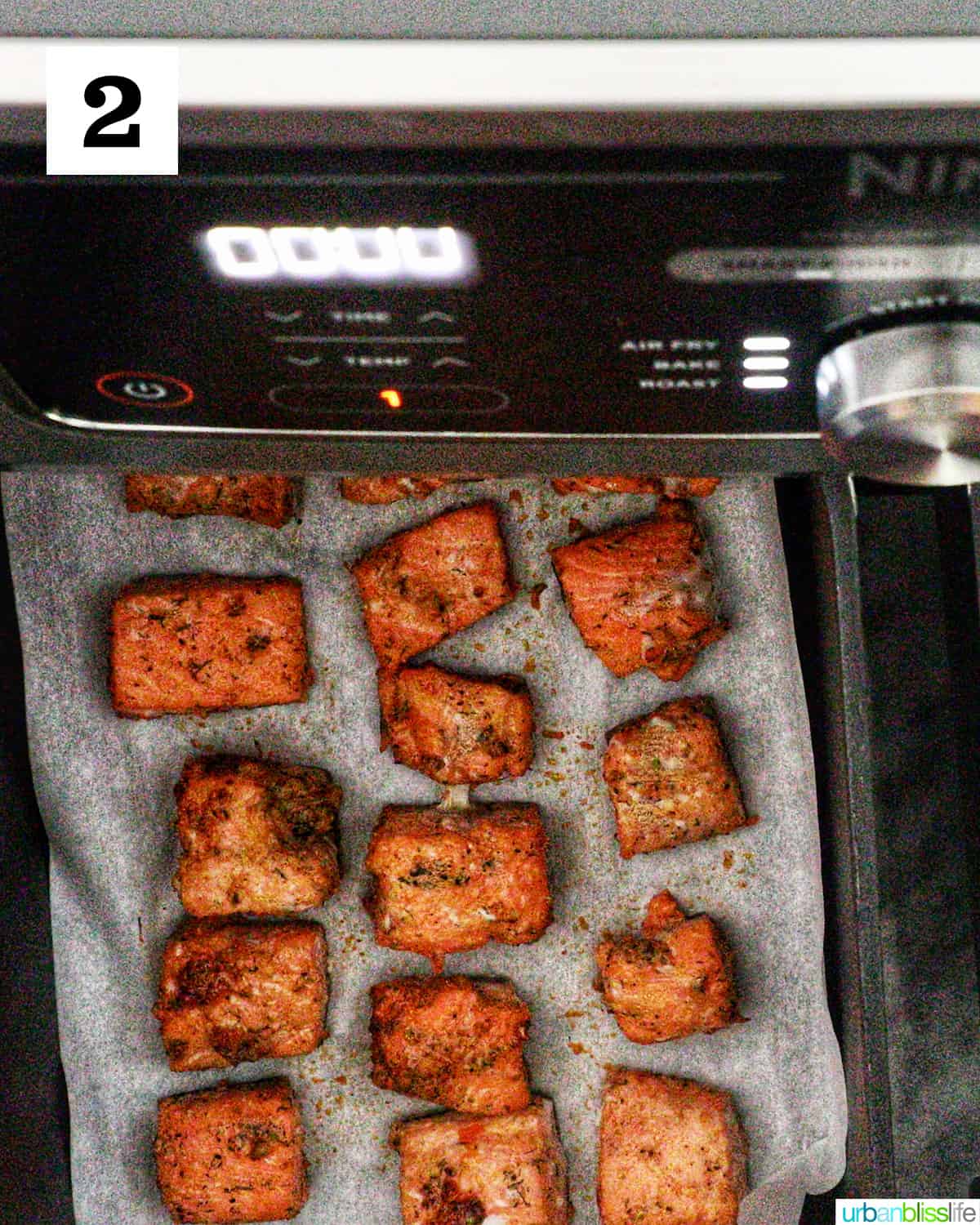 air fryer salmon bites cooked on parchment paper in an air fryer.