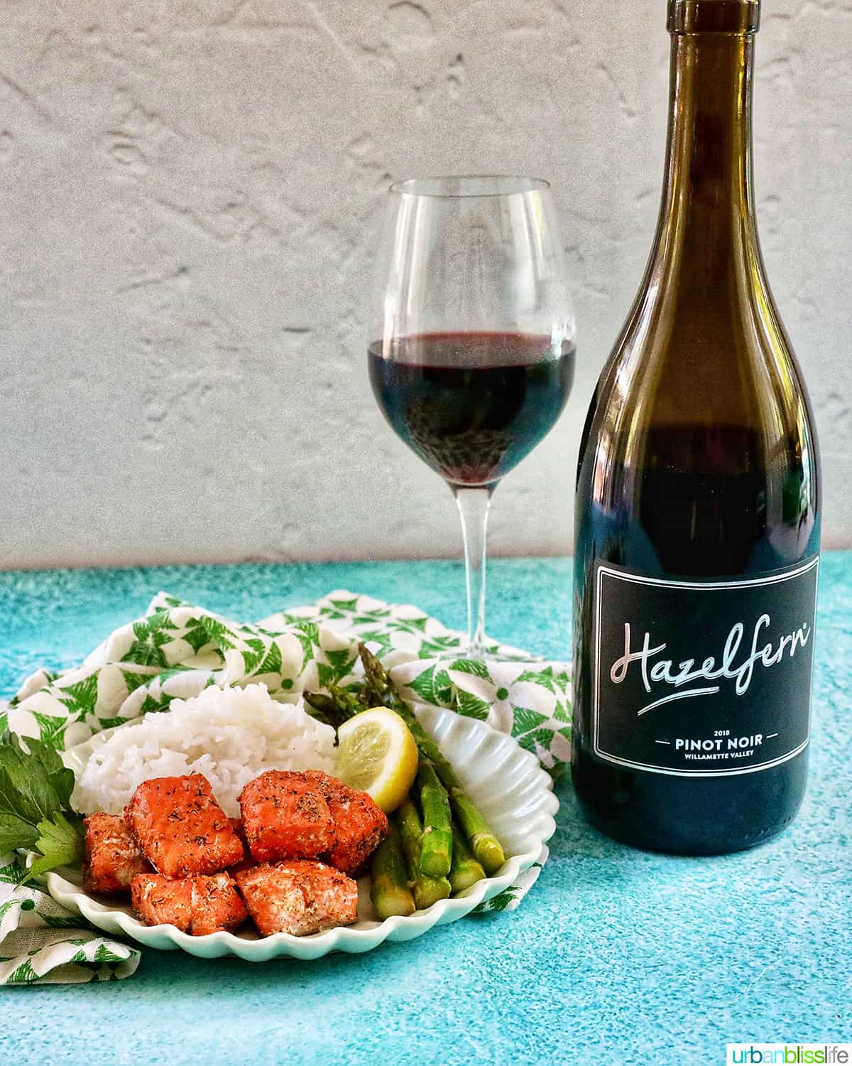air fryer salmon bites with white rice, asparagus, and lemon slice and glass of Pinot Noir wine.