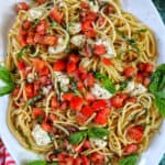bruschetta pasta with tomatoes, basil, mozzarella cheese in a big white serving bowl.