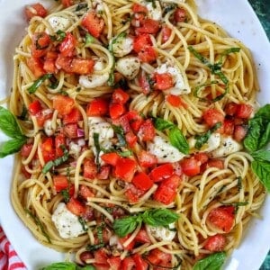 bruschetta pasta with tomatoes, basil, mozzarella cheese in a big white serving bowl.