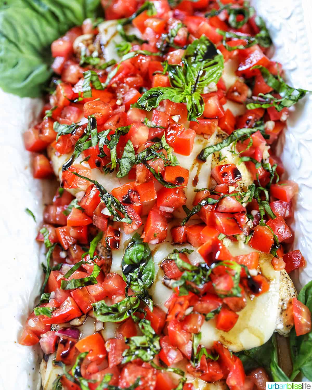 serving platter of chicken bruschetta with tomatoes, basil, and cheese.