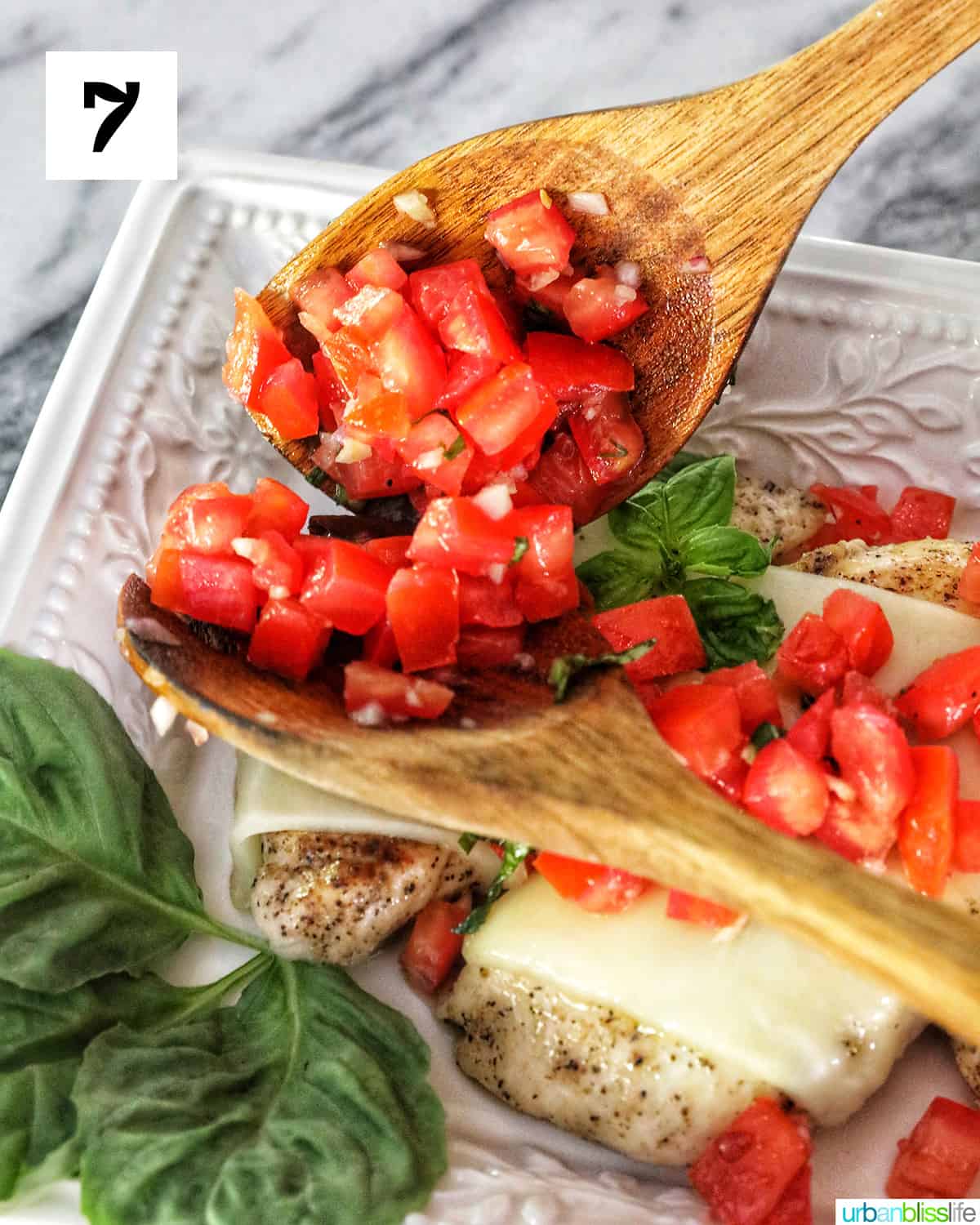 wooden spoons topping chicken bruschetta with diced tomatoes.