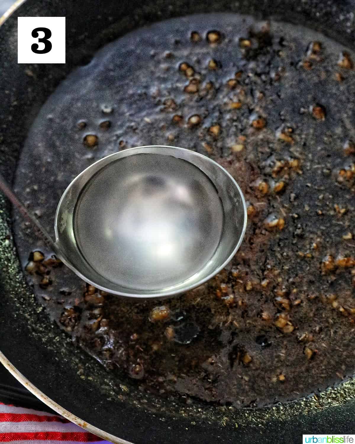 ladle with hot starchy pasta water going into a skillet.