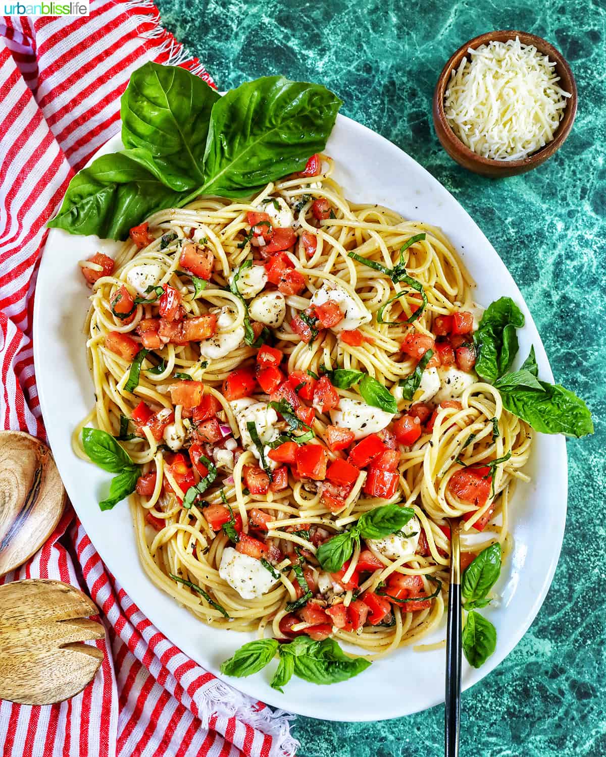 bruschetta pasta with tomatoes, basil, mozzarella cheese in a big white serving bowl.