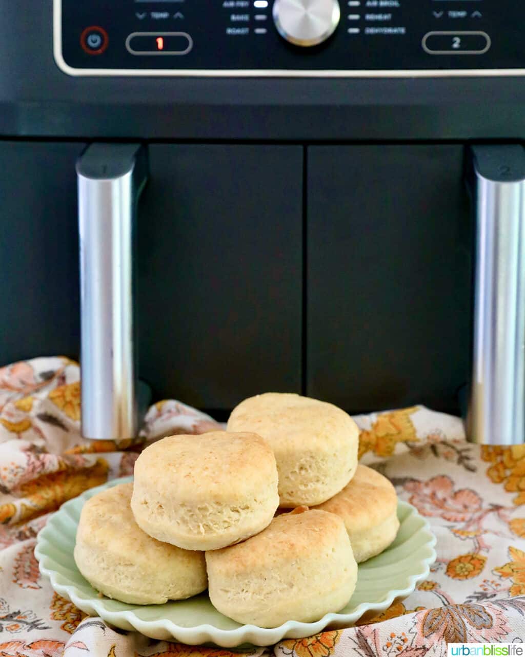 air fryer biscuits stacked on a plate in front of a Ninja Foodi air fryer.