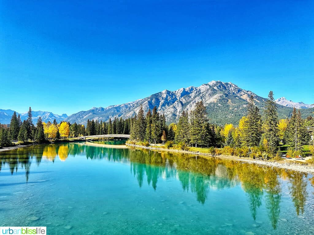 beautiful turquoise blue Bow River, footbridge, and mountains in Banff Canada.