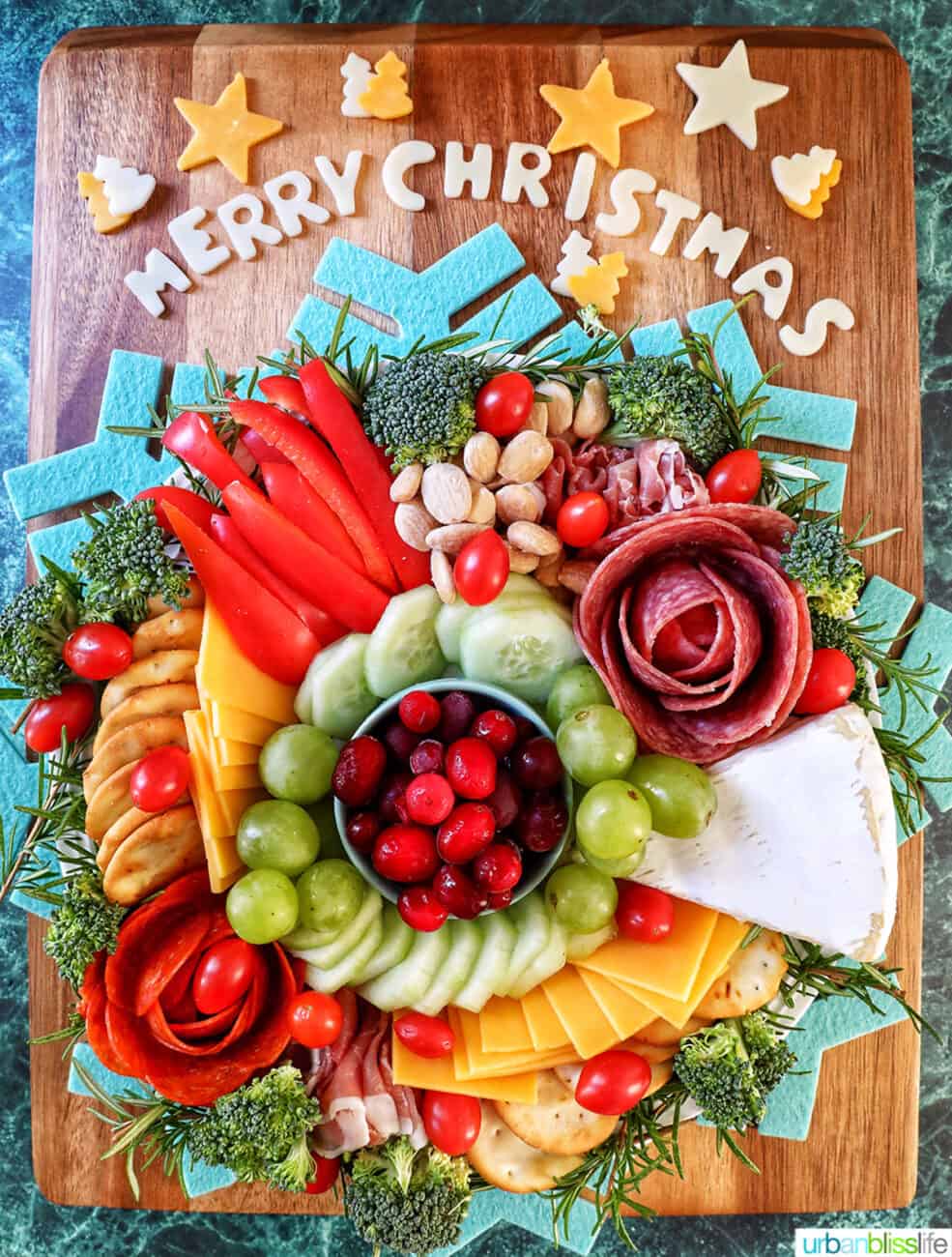 Christmas charcuterie board with variety of meat, cheeses, fruits, vegetables, and nuts.