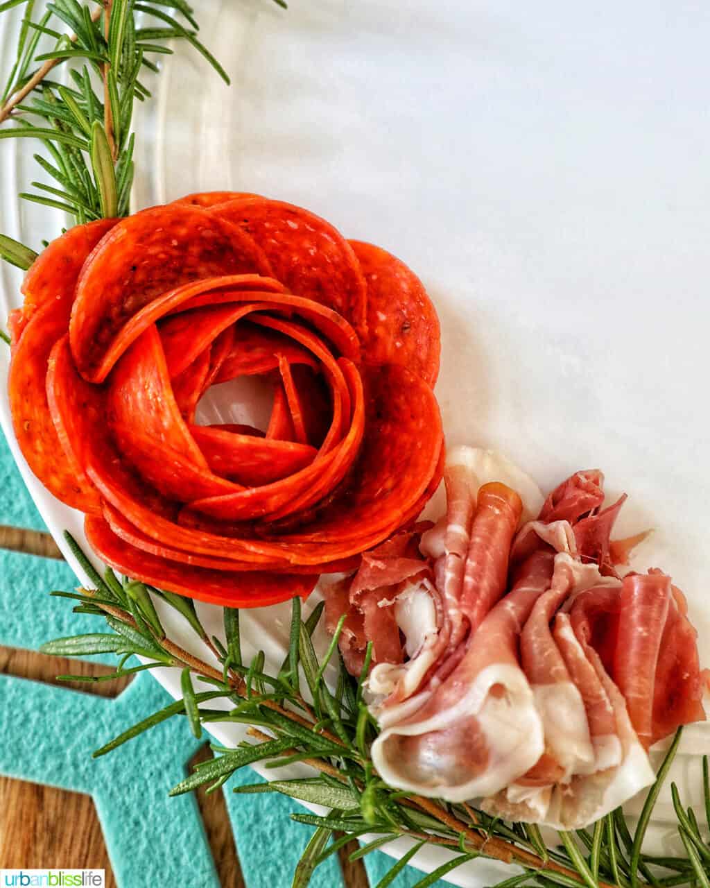 closeup of proscuitto with a pepperoni rose and rosemary sprigs.