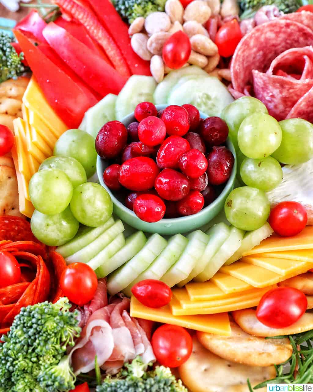 Christmas charcuterie board with variety of meat, cheeses, fruits, vegetables, and nuts.