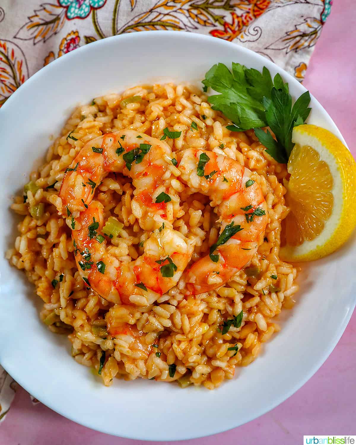 white bowl full of shrimp risotto, with a side of lemon wedge and parsley.