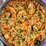 risotto with prawns and herbs in a stainless steel pan.