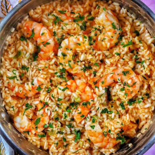 risotto with prawns and herbs in a stainless steel pan.