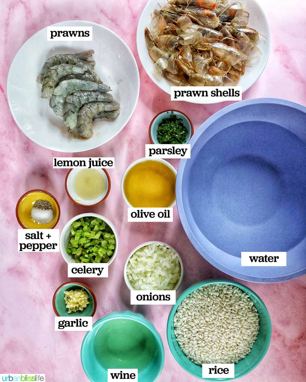 bowls full of ingredients to make risotto with prawns on a pink table.